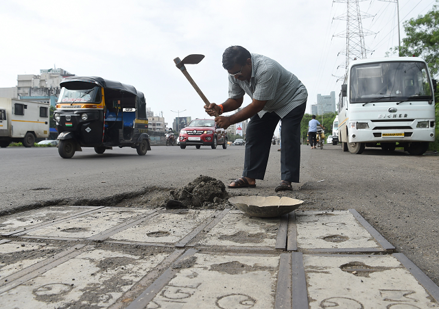 indian businessman dadarao bilhore filling up a pothole on western express highway in mumbai photo afp indian businessman dadarao bilhore filling up a pothole on western express highway in mumbai photo afp