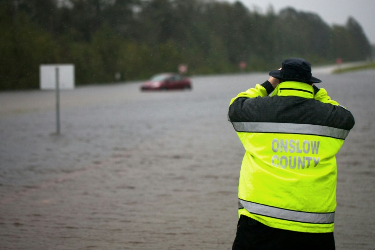 a local emergency official uses binoculars to see if there is anyone inside a car overtaken by flooding on a highway outside of jacksonville north carolina during tropical storm florence photo afp