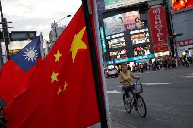 a woman rides a bike past taiwan and china national flags during a rally held in taipei taiwan may 14 2016 photo reuters