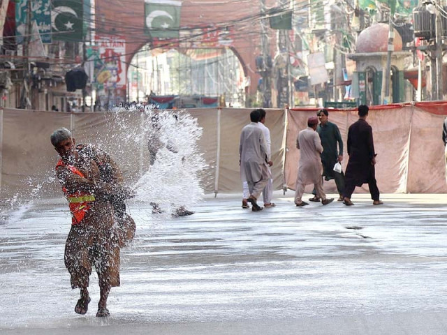 a worker sprinkles water along the route of a moharram procession in qissa khawani bazaar in peshawar photo inp a worker sprinkles water along the route of a moharram procession in qissa khawani bazaar in peshawar photo inp