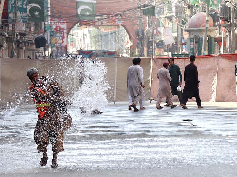 a worker sprinkles water along the route of a moharram procession in qissa khawani bazaar in peshawar photo inp