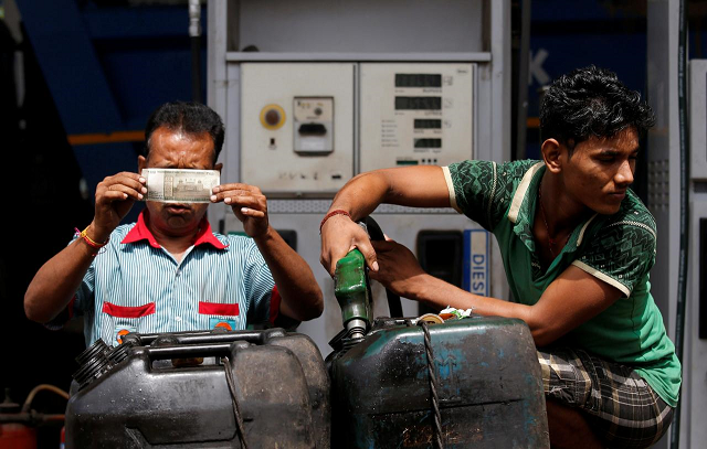 a worker checks a 500 indian rupee note as a man fills diesel in containers at a fuel station in kolkata india august 14 2018 photo reuters