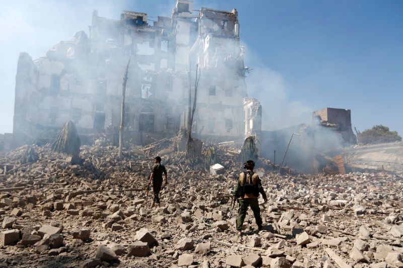huthi rebel fighters inspect the damage after a reported air strike by the saudi led coalition in sanaa photo afp