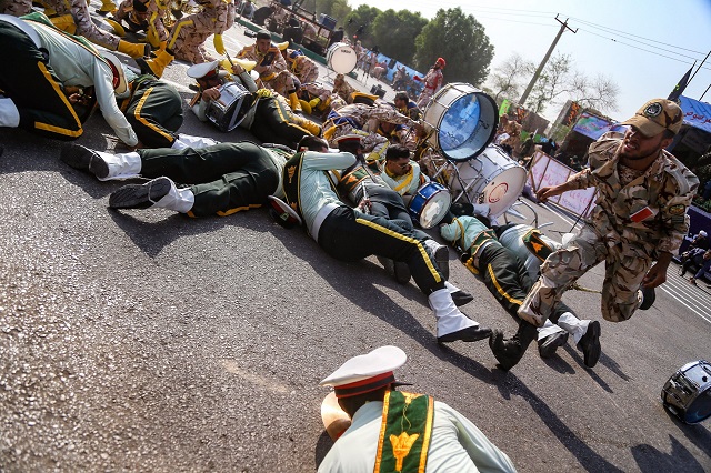 this picture taken on september 22 2018 in the southwestern iranian city of ahvaz shows a soldier running past injured comrades lying on the ground at the scene of an attack on a military parade photo afp