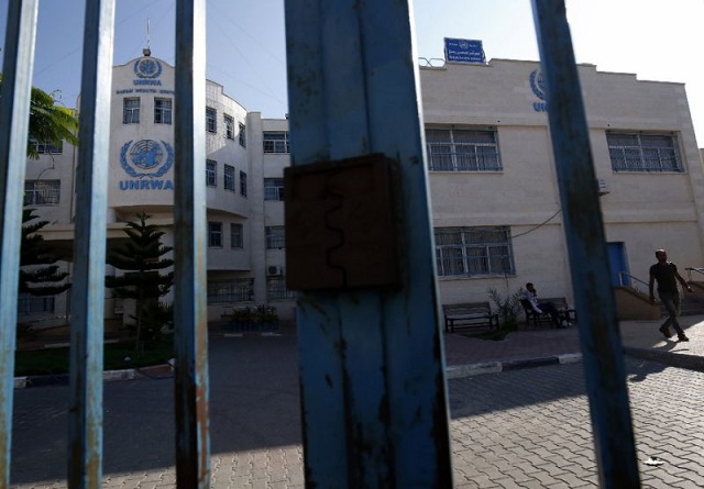 palestinians are seen behind the closed gate of the united nations relief and works agency unrwa during a strike by employees in the gaza strip on september 24 2018 photo afp