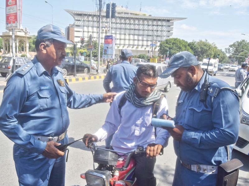 traffic policemen issue a challan to a motorcyclist on mall road for not wearing a helmet photo nni