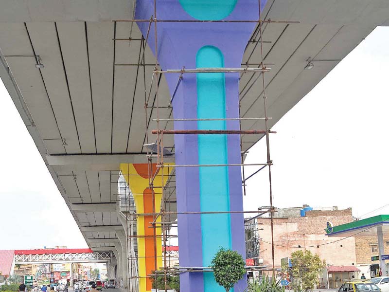 workers paint pillars of metro bus track near liaquat bagh in rawalpindi photo inp