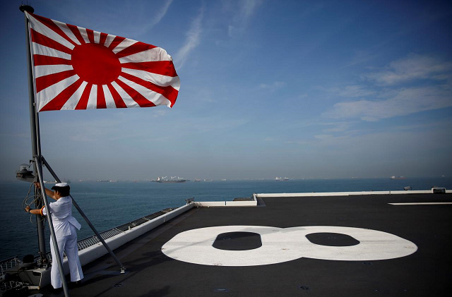 a sailor raises the japanese naval ensign on the deck of japanese helicopter carrier kaga before its departure for naval drills in the indian ocean indonesia september 22 2018 photo reuters