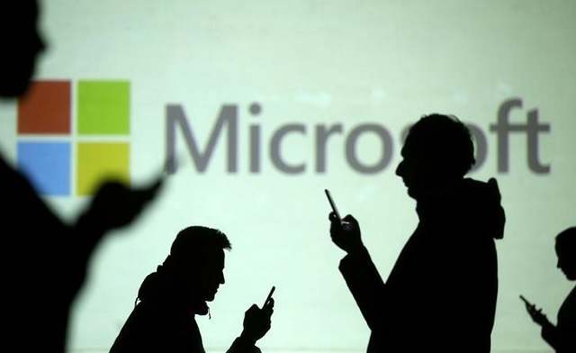 silhouettes of mobile users are seen next to a screen projection of microsoft logo in this picture illustration taken march 28 2018 photo reuters