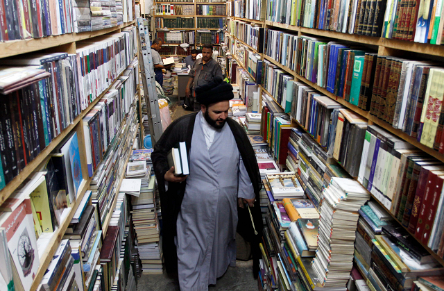 a man walks among books shelves at the howeish book market in the iraqi city of najaf photo afp