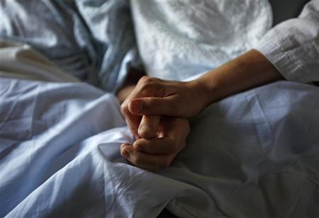 a woman holds the hand of her mother who is dying from cancer during her final hours at a palliative care hospital photo reuters