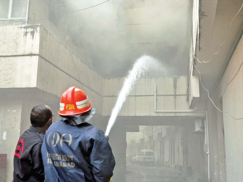 a fireman sprays water on flames while a soldier stands next to employees at the pid building following a fire on wednesday photos agencies