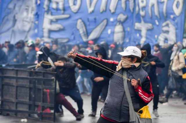 a demonstrator in argentina fires a slingshot at riot police outside congress ahead of a vote photo afp a demonstrator in argentina fires a slingshot at riot police outside congress ahead of a vote photo afp