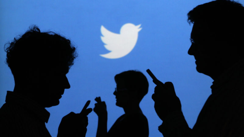 people holding mobile phones are silhouetted against a backdrop projected with the twitter logo in this illustration picture taken in warsaw photo reuters