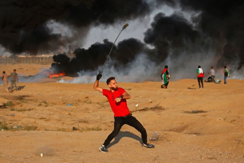 a palestinian protester uses a slingshot to throw a rock at israeli forces along the israel gaza border east of gaza city photo afp