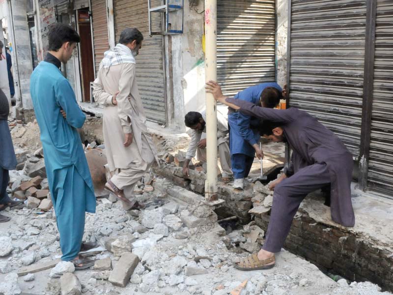 a shopkeeper puts labourers to work to remove encroached extension of his shop before demolition squads of civic authorities come with excavators photo express