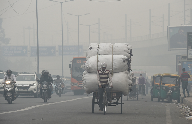 an indian man r with his face covered walks amid heavy smog along a street in new delhi on november 5 2018 photo afp