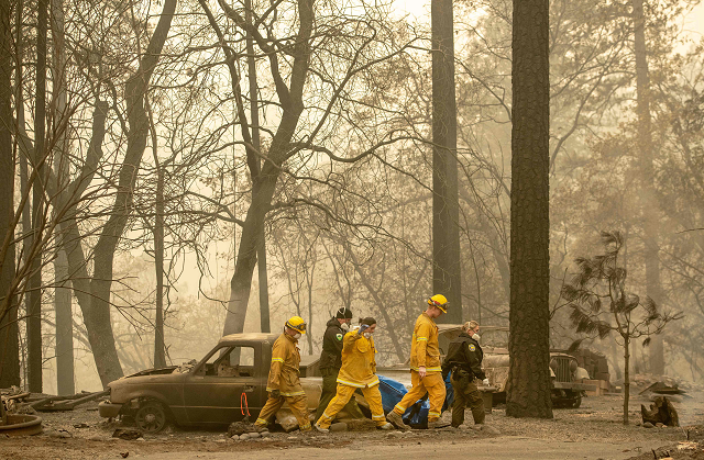 rescue workers carry a body away from a burned property in the holly hills area of paradise photo afp