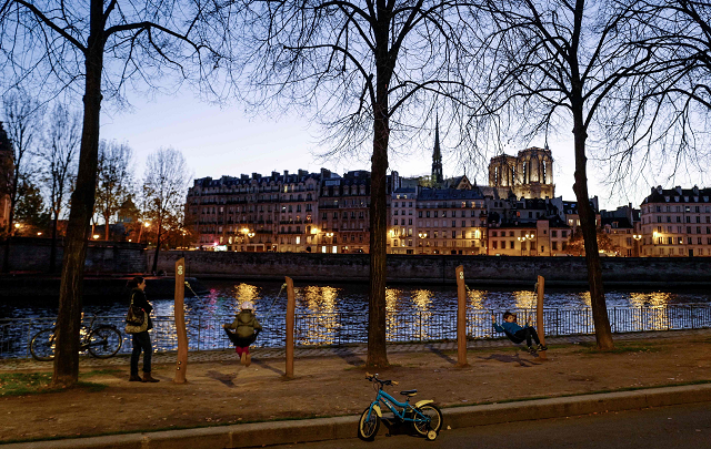 children play on swings on november 14 2018 in central paris on the river seine pedestrian banks facing the ile de la cit island and notre dame de paris cathedral photo afp