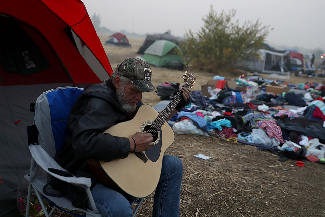 camp fire evacuee kelly boyer plays guitar in front of his tent next to a walmart parking photo afp