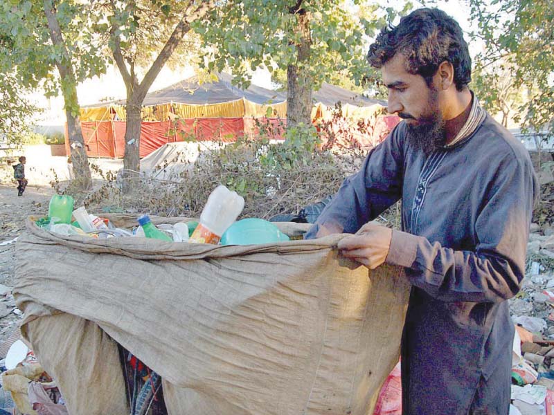 a ragpicker collects recyclable items from a garbage dump in islamabad photo app