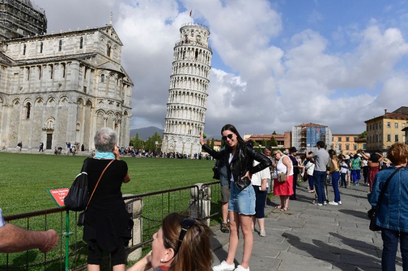 tourists pose for photographs at the tower of pisa in 2017 photo afp
