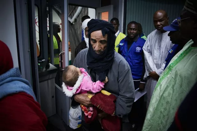 a man carries a baby as malian migrants arrive in bamako on december 13 2017 after being repatriated from libya by the international organization for the migration which is operating a voluntary return programme photo afp a man carries a baby as malian migrants arrive in bamako on december 13 2017 after being repatriated from libya by the international organization for the migration which is operating a voluntary return programme photo afp