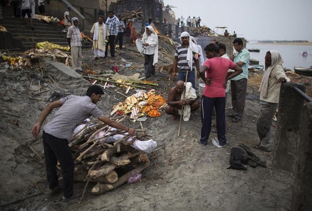 a man places wood on a funeral pyre at a cremation on the banks of river ganges in varanasi in uttar pradesh june 19 2014 the city of varanasi on the banks of the river ganges is widely considered hinduism 039 s holiest city and many hindus believe that dying there and having their remains scattered in the ganges allows their soul to escape a cycle of death and rebirth attaining quot moksha quot or salvation photo reuters