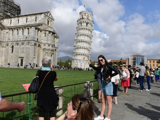 tourists pose for photographs at the tower of pisa photo afp tourists pose for photographs at the tower of pisa photo afp