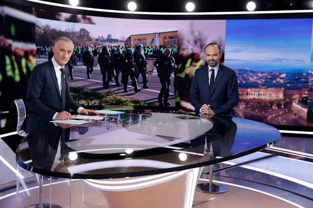 french prime minister edouard philippe r and french tv host gilles bouleau pose during the evening news broadcast of french tv channel tf1 on december 6 2018 in the tf1 studios in boulogne billancourt near paris on the eve of a new quot yellow vests quot national demonstration on december 8 2018 photo afp