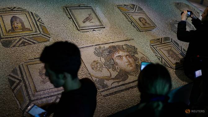 visitors take pictures of the missing pieces of the historic gypsy girl mosaic on display in an exhibition at their origin in gaziantep turkey photo afp