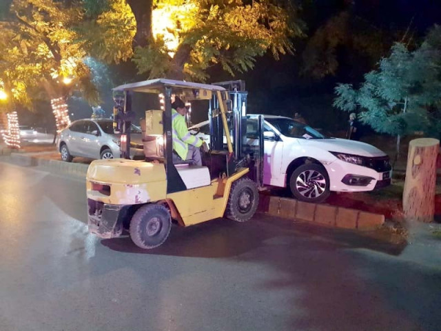 a traffic police official uses a fork lift to remove a car which was incorrectly parked photo express a traffic police official uses a fork lift to remove a car which was incorrectly parked photo express