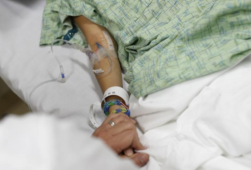 a doctor holds the hand of a patient in a hospital emergency room photo reuters