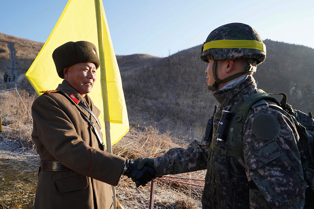 this handout photo taken on december 12 2018 and provided by south korean defence ministry shows a south korean soldier r shaking hands with a north korean soldier l before crossing the military demarcation line to inspect the dismantled north korean guard post inside the demilitarised zone dmz dividing the two koreas in cheorwon photo afp