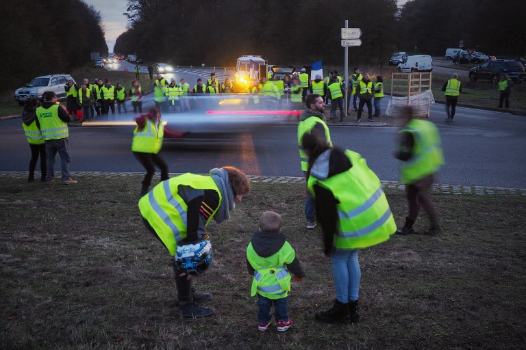 protestors wearing yellow vests gilets jaunes stand at a roundabout to block access to a commercial center in blois central france photo afp
