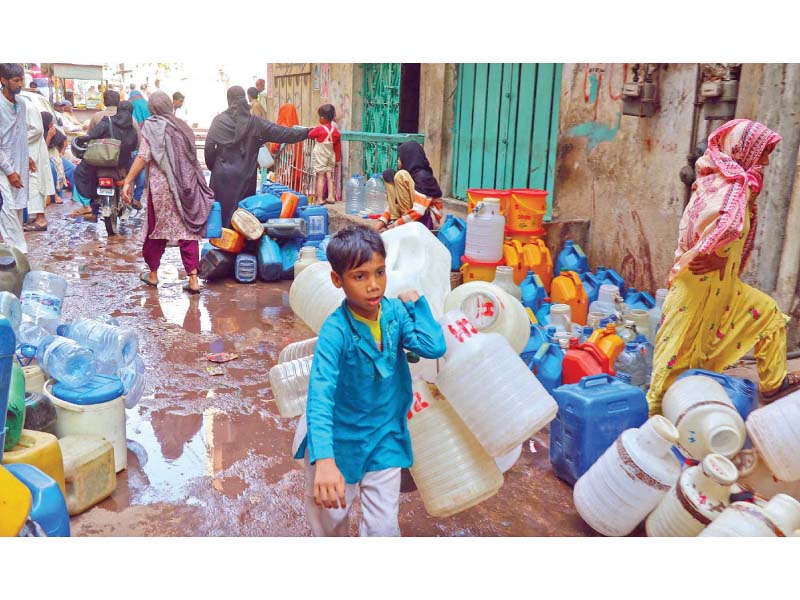 a child in lyari carries multiple cans to fetch water residents are forced to wait in long queues to fill cans and other utensils with water for use at their homes photo online