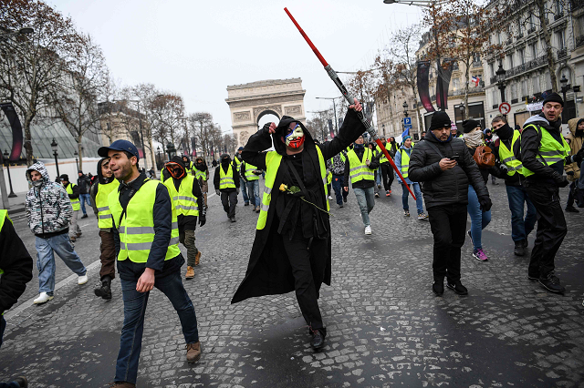a man wearing an anonymous mask and a yellow vest gilet jaune and holding a star wars jedi light laser takes part in a demonstration to protest against rising costs of living they blame on high taxes by the arc de triomphe in paris on december 15 2018 photo afp a man wearing an anonymous mask and a yellow vest gilet jaune and holding a star wars jedi light laser takes part in a demonstration to protest against rising costs of living they blame on high taxes by the arc de triomphe in paris on december 15 2018 photo afp