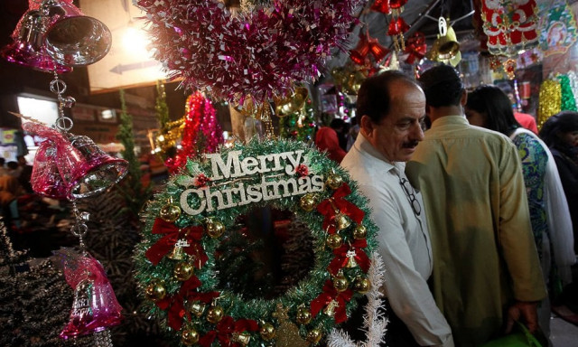 people walk past an artificial decoration wreath hanging outside a shop selling various items for christmas celebrations in karachi photo reuters people walk past an artificial decoration wreath hanging outside a shop selling various items for christmas celebrations in karachi photo reuters