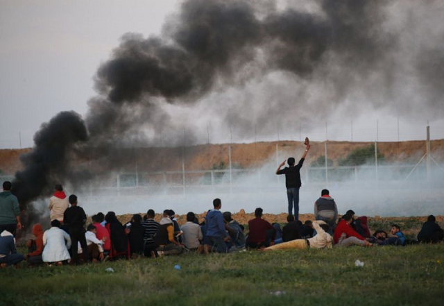 palestinian protesters crouch down as others burn tyres during a demonstration near the border between israel and khan yunis in the southern gaza strip photo afp
