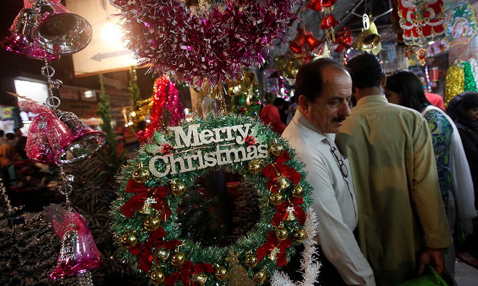 people walk past an artificial decoration wreath hanging outside a shop selling various items for christmas celebrations in karachi photo reuters