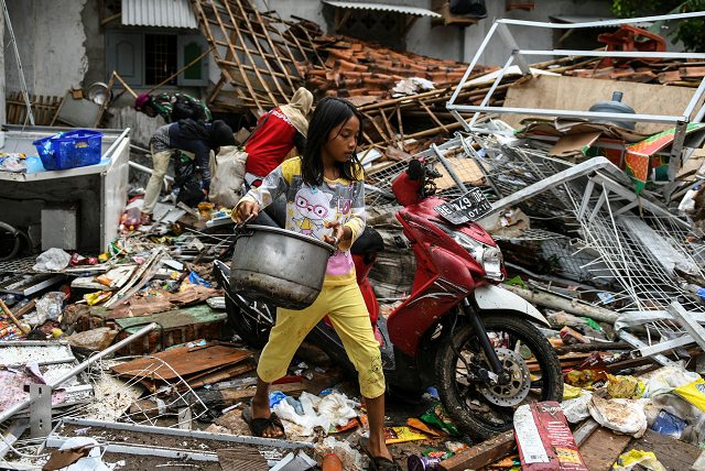 a girl carries her belongings from her collapsed home in rajabasa in lampung province photo afp a girl carries her belongings from her collapsed home in rajabasa in lampung province photo afp