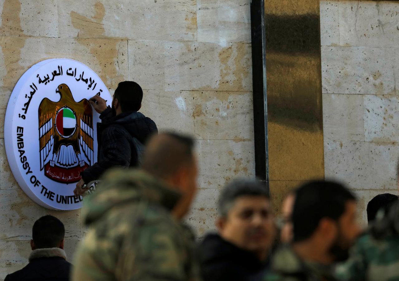 a man works on the emblem of the united arab emirates embassy in damascus during its reopening syria photo reuters