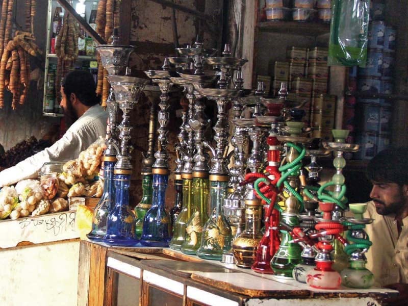 a vendor displays water pipes and its tobacco to attract customers in karachi photo online