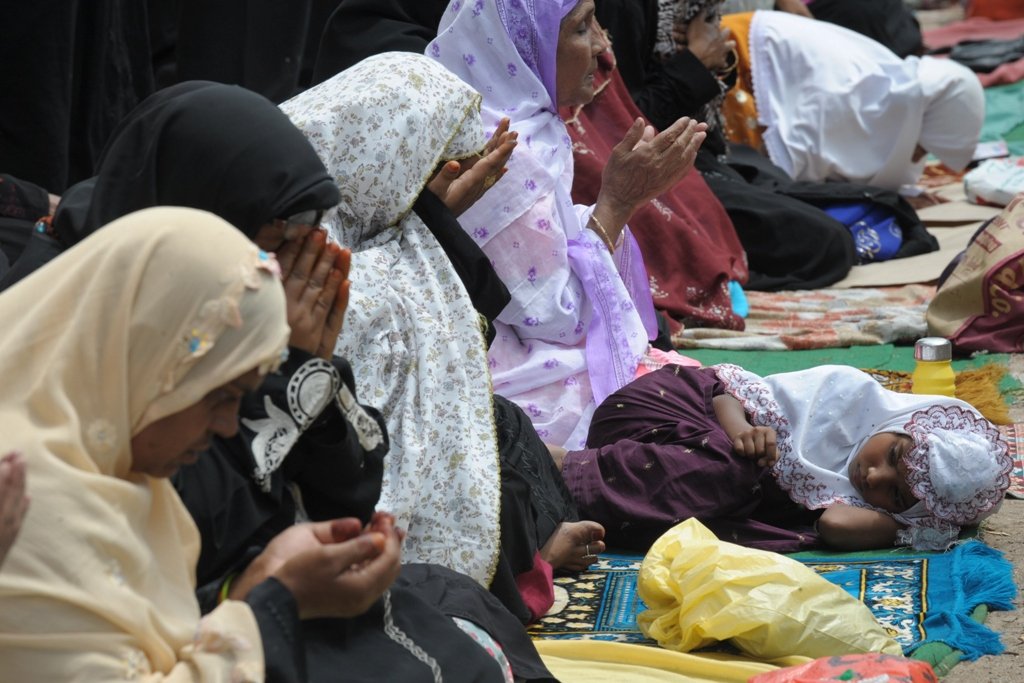 a child rests as indian muslim women offer jumat ul vida prayers on the last friday of ramazan outside the historic mecca masjid in hyderabad on august 17 2012 ahead of the eid ul fitr festival photo afp