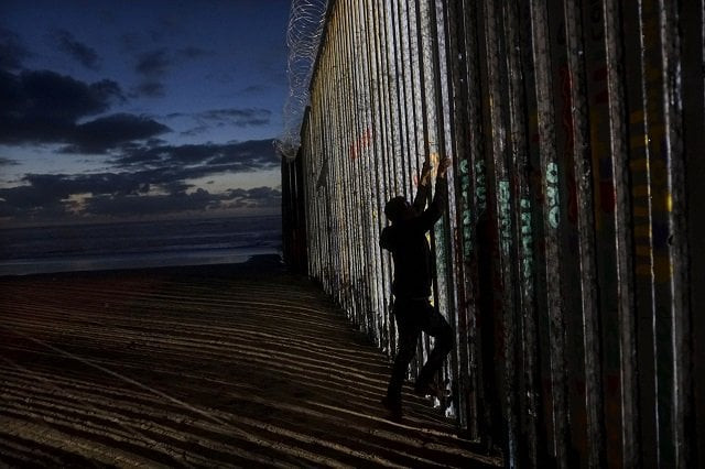 a man prepares to climb on the u s mexico border wall on january 6 2019 in tijuana mexico photo afp a man prepares to climb on the u s mexico border wall on january 6 2019 in tijuana mexico photo afp