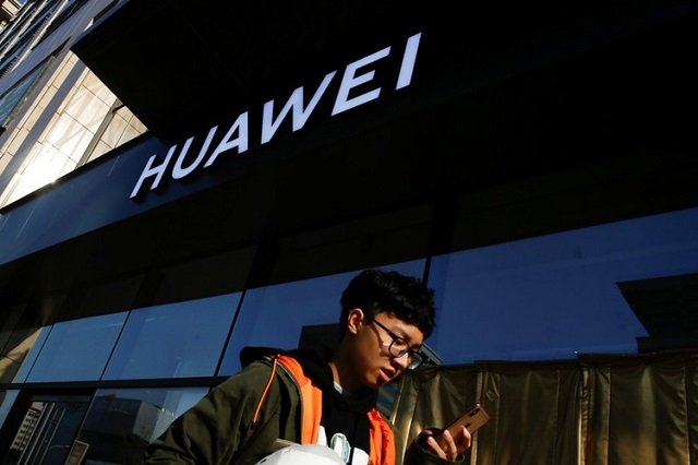 a man uses his phone as he walks past a huawei shop in beijing china december 19 2018 photo reuters