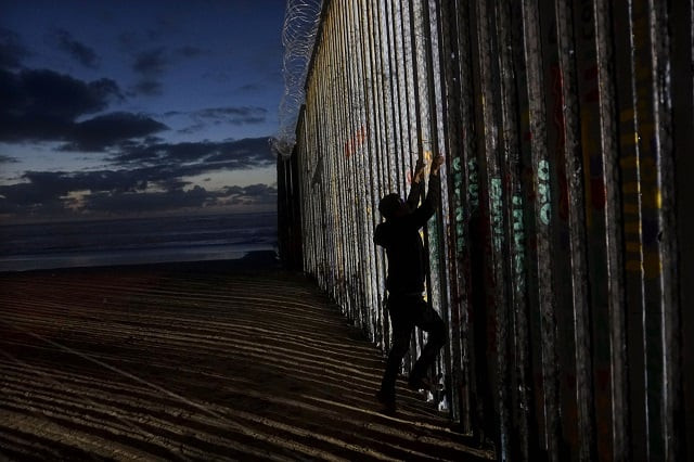 a man prepares to climb on the u s mexico border wall on january 6 2019 in tijuana mexico photo afp a man prepares to climb on the u s mexico border wall on january 6 2019 in tijuana mexico photo afp