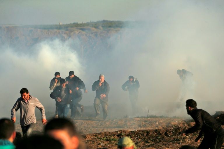 palestinian protesters run through tear gas fumes during clashes with israeli forces during a demonstration along the border with israel east of gaza city photo afp
