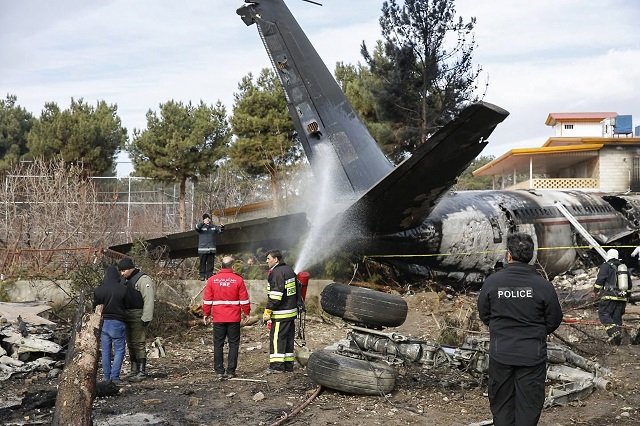 firefighters and security forces gather amidst the debris of a boeing 707 cargo plane that reportedly crashed into a residential complex near the iranian capital tehran with 10 people onboard on january 14 2019 photo afp