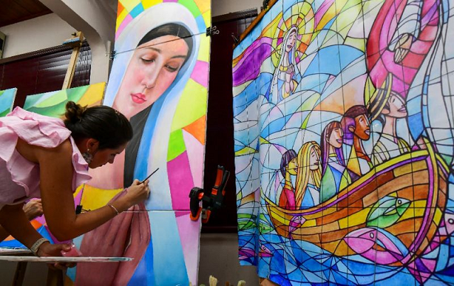 a woman works on a panel that will be part of a giant mural forming the backdrop to a papal mass during world youth day celebrations in panama photo afp